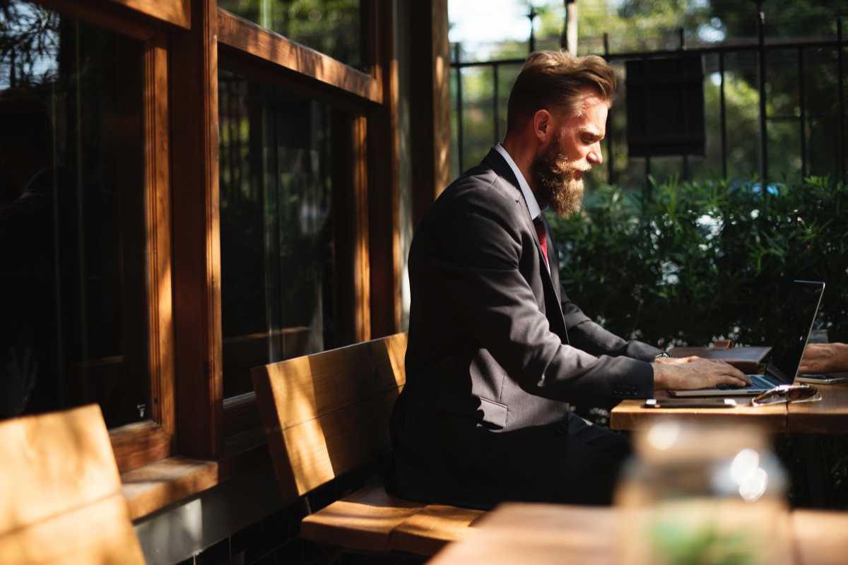 Young blond man with bg berd in suite working from cafe